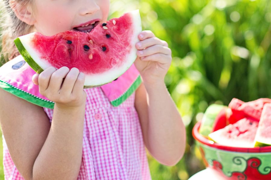 A child happily eating a slice of watermelon outdoors
