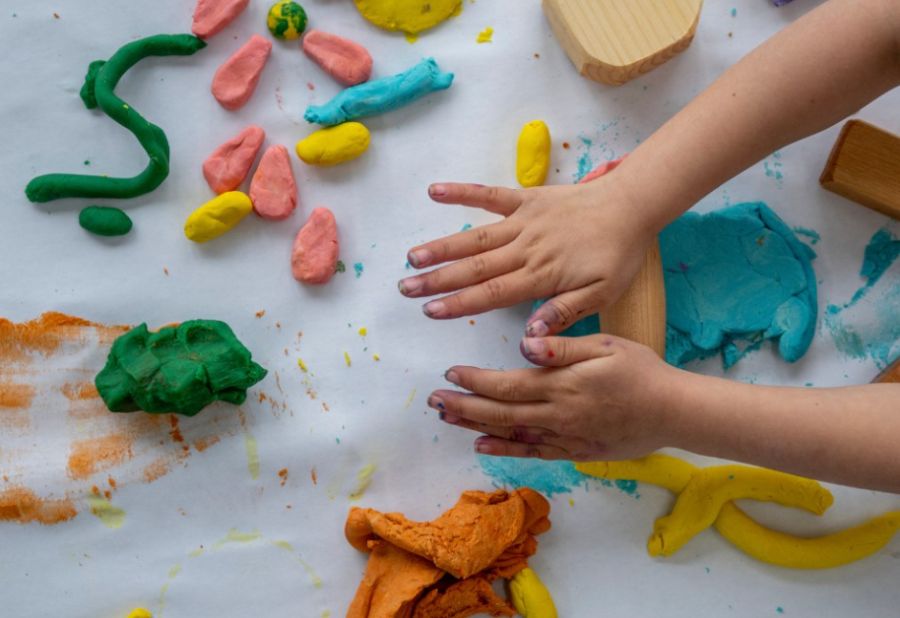 A child's hands shaping colourful playdough
