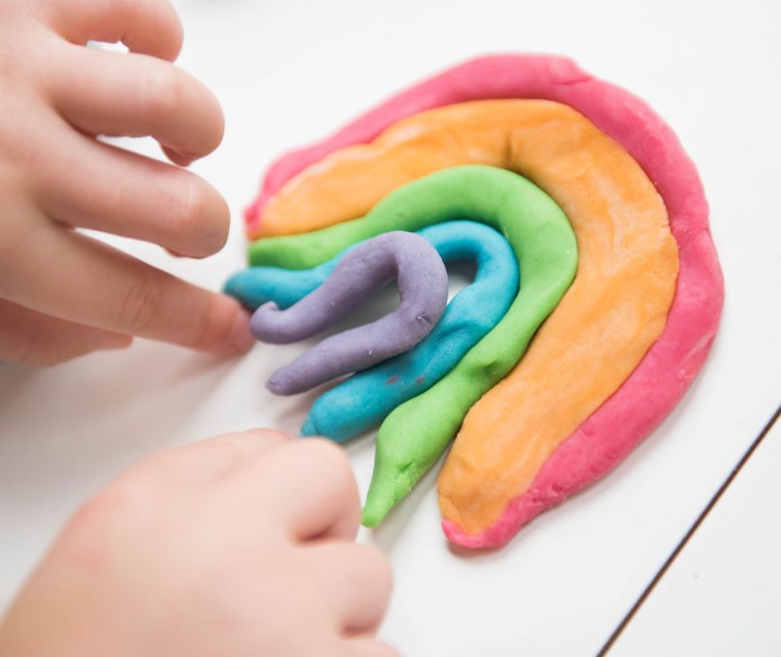 A child shaping a rainbow out of colourful playdough