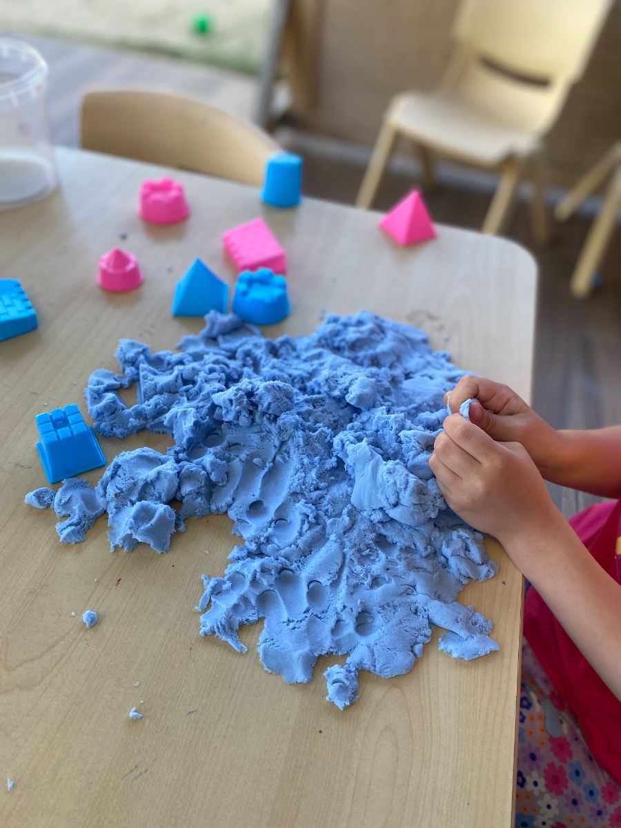 A child engaged in sensory play with kinetic sand