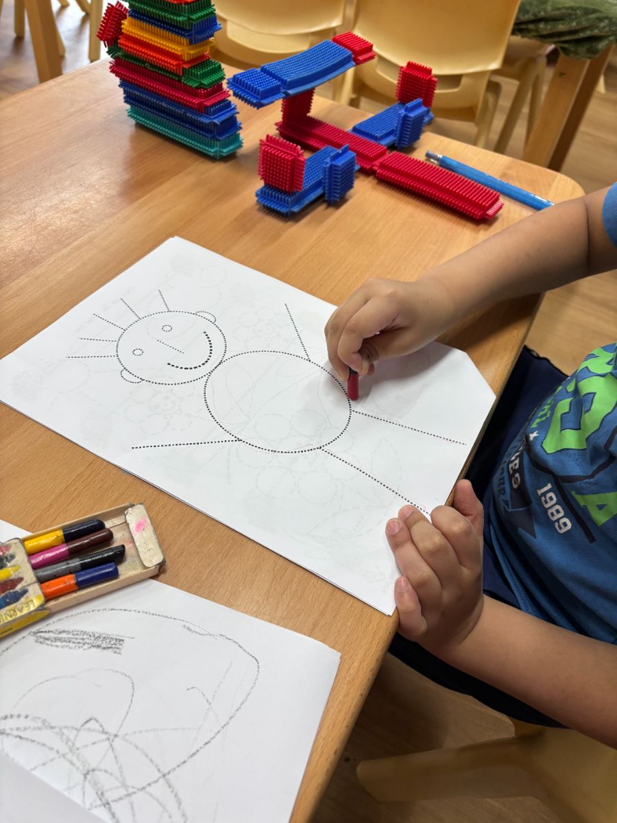A child practising fine motor skills with crayons at a table